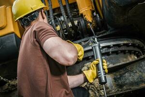 Construction Worker Performing Excavator Maintenance photo