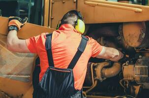 reparador inspeccionando y ajustando motor en excavadora. foto