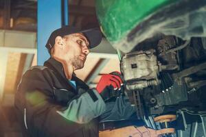 Mechanic Repairing Vehicle Suspended On Car Lift. photo