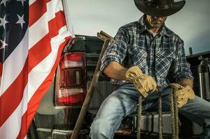 vaquero ranchero asientos en su recoger camión carga cama con un cuerda en su manos foto