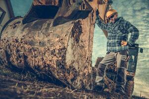 Construction Worker in Front of Excavator Bucket photo