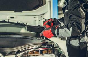 Car Mechanic Looking For Burned Fuse Under Vehicle Hood photo