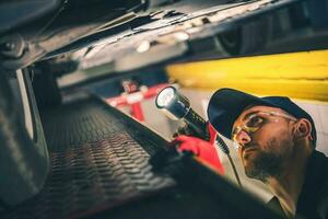 Mechanic Checking Car Undercarriage During Regular Vehicle Inspection photo