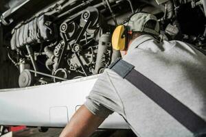 Diesel Technician Looking Inside Bus Engine Compartment photo