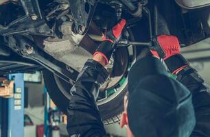 Automotive Caucasian Mechanic Working Under a Vehicle photo