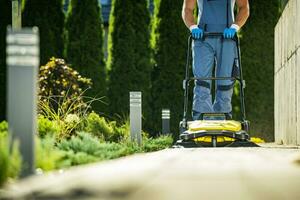 Landscaper Worker with Push Sweeper Cleaning Garden Pathway photo