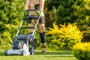 Garden Worker with Lawnmower Cutting Grass photo