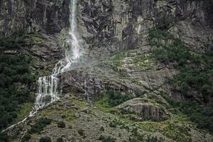 alto cascada en Noruega fluye abajo ladera de la montaña foto