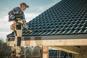 Male Worker Installing Roof Shingles. photo