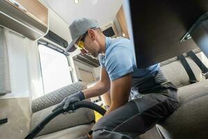 Man Vacuuming a Sofabed in a Recreational Camper Van photo