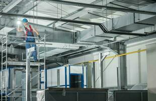 Professional HVAC Technician with Flashlight Overlooking Finished Air Ventilation System photo