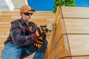 Painter Oiling Wooden Planks With Brush. photo