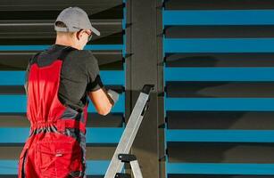 Worker Finishing Installation of Modern Pergola Wall Shade Shutters photo