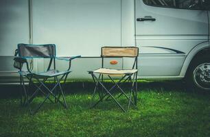 Two Empty Camping Deckchairs in Front of RV Camper photo