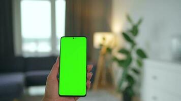 vrouw Bij huis gebruik makend van smartphone met groen mock-up scherm in verticaal modus. meisje browsen internetten, aan het kijken inhoud video