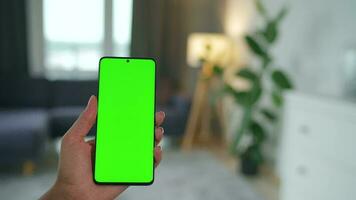 vrouw Bij huis gebruik makend van smartphone met groen mock-up scherm in verticaal modus. meisje browsen internetten, aan het kijken inhoud video