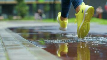 Female sports woman jogging outdoors, stepping into puddle. Single runner running in rain, making splash. Slow motion video