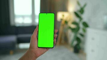 vrouw Bij huis gebruik makend van smartphone met groen mock-up scherm in verticaal modus. meisje browsen internetten, aan het kijken inhoud video