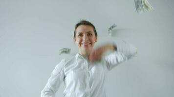 Happy formally dressed woman making money rain from dollar bills. Slow motion video