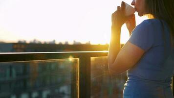 donna con un' tazza di caffè in piedi su il balcone e ammirare il tramonto video