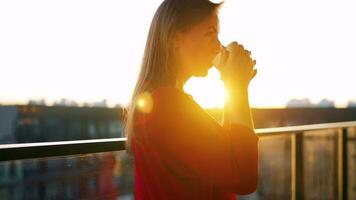 Frau mit ein Tasse von Kaffee Stehen auf das Balkon und bewundern das Sonnenuntergang video