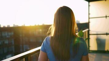 vrouw met een kop van koffie staand Aan de balkon en bewonderen de zonsondergang video