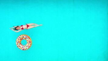 View from the top as a woman in red swimsuit lying on her back in the pool. Relaxing concept video