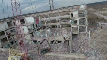 fpv zumbido moscas suavemente entre abandonado industrial edificios y alrededor un excavador video