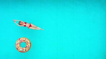 Aussicht von das oben wie ein Frau im rot Badeanzug Lügen auf ihr zurück im das Schwimmbad. entspannend Konzept video