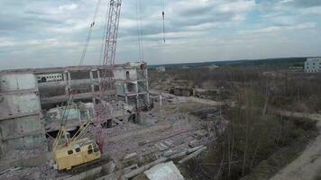 fpv zumbido moscas suavemente entre abandonado industrial edificios y alrededor un excavador video