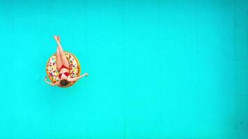 Aerial view of a woman in red bikini swimming on a donut in the pool video