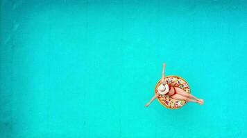 Aerial view of a woman in red bikini swimming on a donut in the pool video