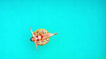 Aerial view of a woman in red bikini swimming on a donut in the pool video