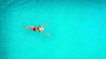 Aussicht von das oben wie ein Frau im rot Badeanzug Lügen auf ihr zurück im das Schwimmbad. entspannend Konzept video