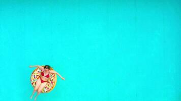 Aerial view of a woman in red bikini swimming on a donut in the pool video