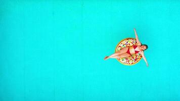 Aerial view of a woman in red bikini swimming on a donut in the pool video