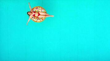 Aerial view of a woman in red bikini swimming on a donut in the pool video