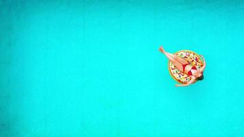 Aerial view of a woman in red bikini swimming on a donut in the pool video