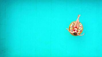 Aerial view of a woman in red bikini swimming on a donut in the pool video