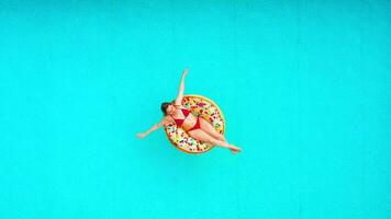 Aerial view of a woman in red bikini swimming on a donut in the pool video