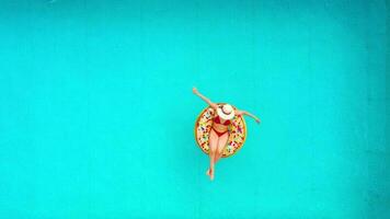 Aerial view of a woman in red bikini swimming on a donut in the pool video