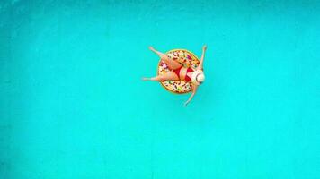 Aerial view of a woman in red bikini swimming on a donut in the pool video