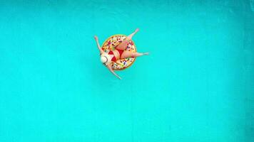 aéreo Visão do uma mulher dentro vermelho bikini natação em uma rosquinha dentro a piscina video