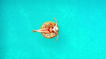 Aerial view of a woman in red bikini swimming on a donut in the pool video