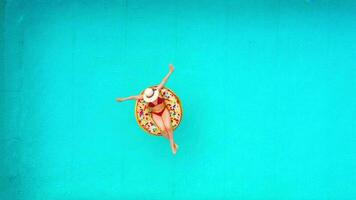 Aerial view of a woman in red bikini swimming on a donut in the pool video