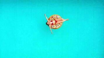 Antenne Aussicht von ein Frau im rot Bikini Schwimmen auf ein Krapfen im das Schwimmbad video