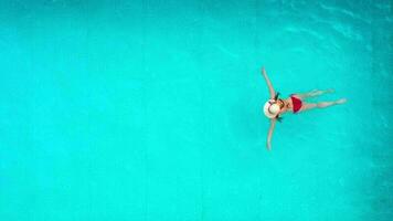 Aussicht von das oben wie ein Frau im rot Badeanzug Lügen auf ihr zurück im das Schwimmbad. entspannend Konzept video
