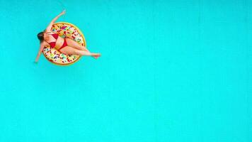 Aerial view of a woman in red bikini swimming on a donut in the pool video