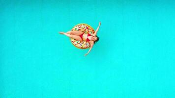 Aerial view of a woman in red bikini swimming on a donut in the pool video