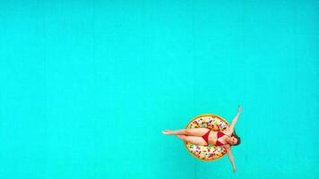 Aerial view of a woman in red bikini swimming on a donut in the pool video